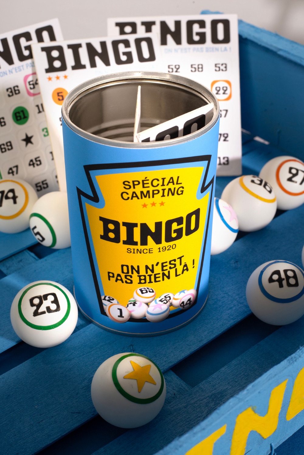 La boîte de jeu, une conserve habillée de l’étiquette Bingo, posée sur un banc bleu au milieu des boules.
