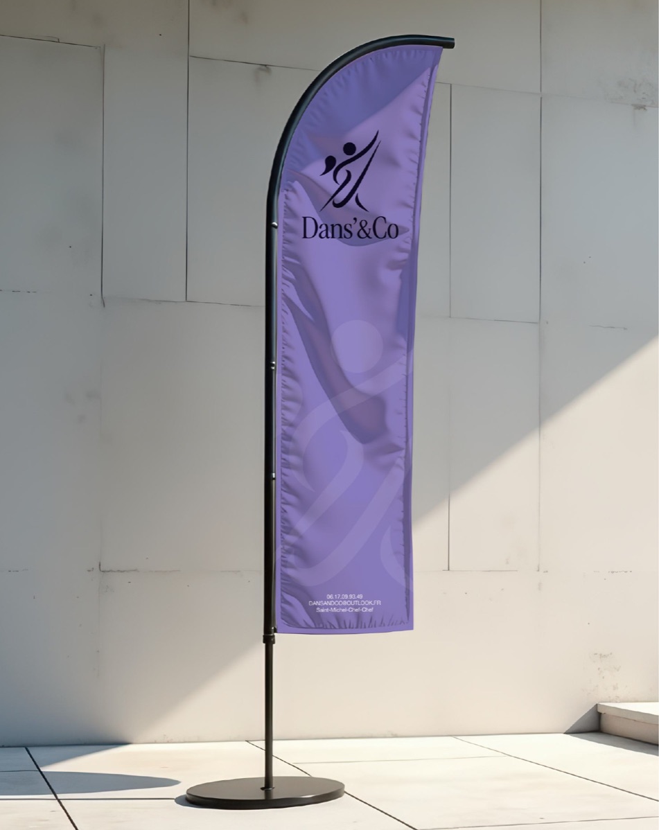 Oriflamme violette au logo du studio, dressée contre un mur clair.