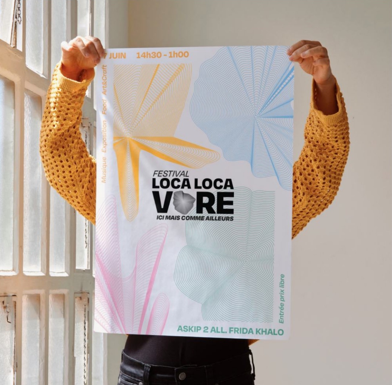 Loca Locavore — l’affiche du festival tenue à bout de bras devant une fenêtre.