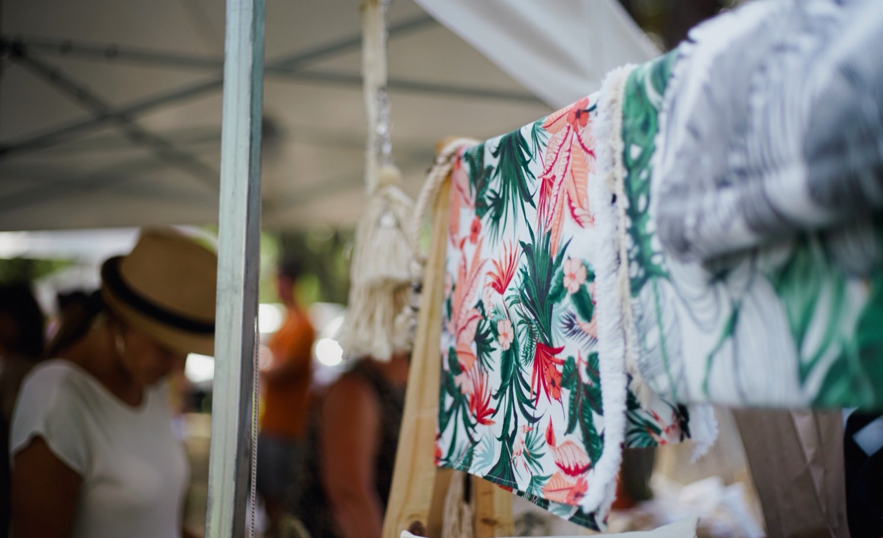 Un stand du marché, un plaid à motifs végétaux suspendu à une tringle.