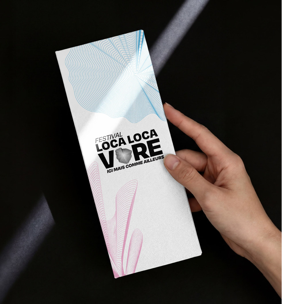 Le dépliant fermé, tenu dans un rai de lumière sur fond noir.