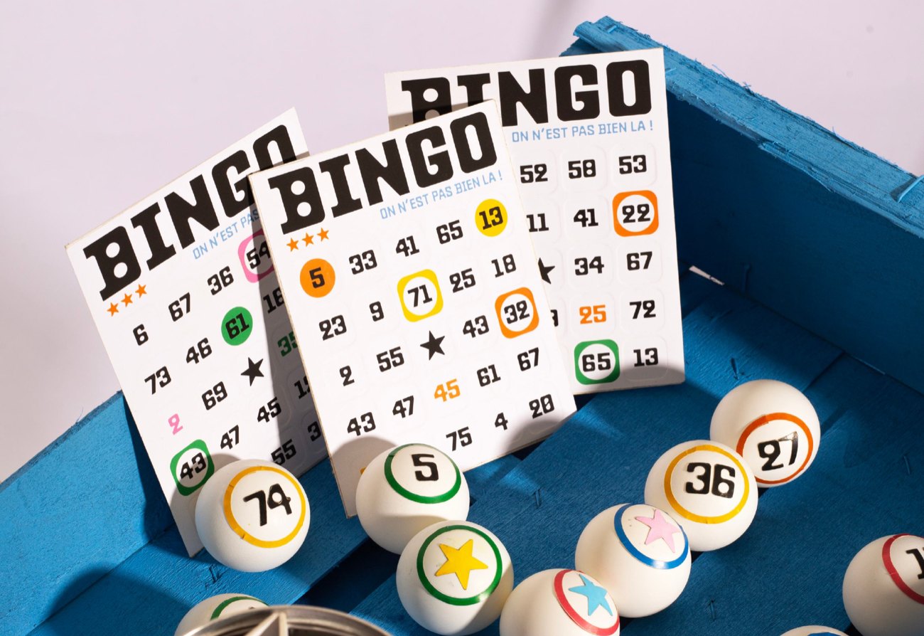 Cartons de bingo et boules de loto posés sur un tissu bleu.