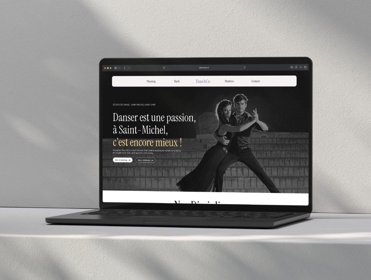 Le site de Dans’&Co affiché sur un ordinateur portable, posé devant un mur clair.