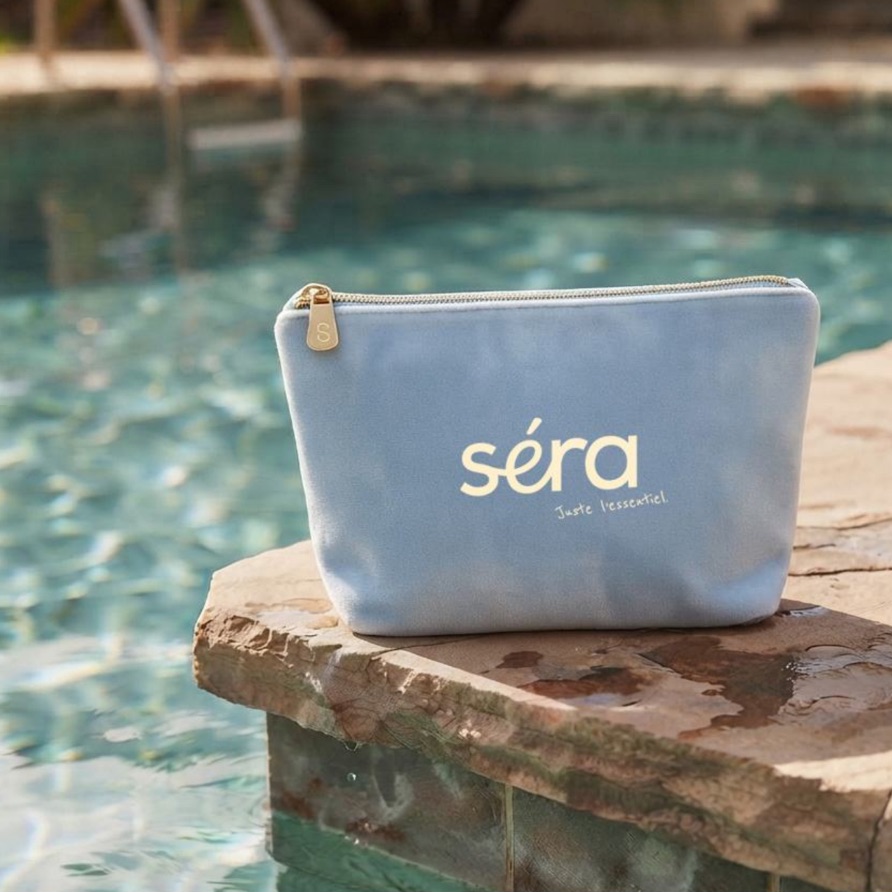 Séra — trousse en toile bleu pâle posée au bord d’une piscine.