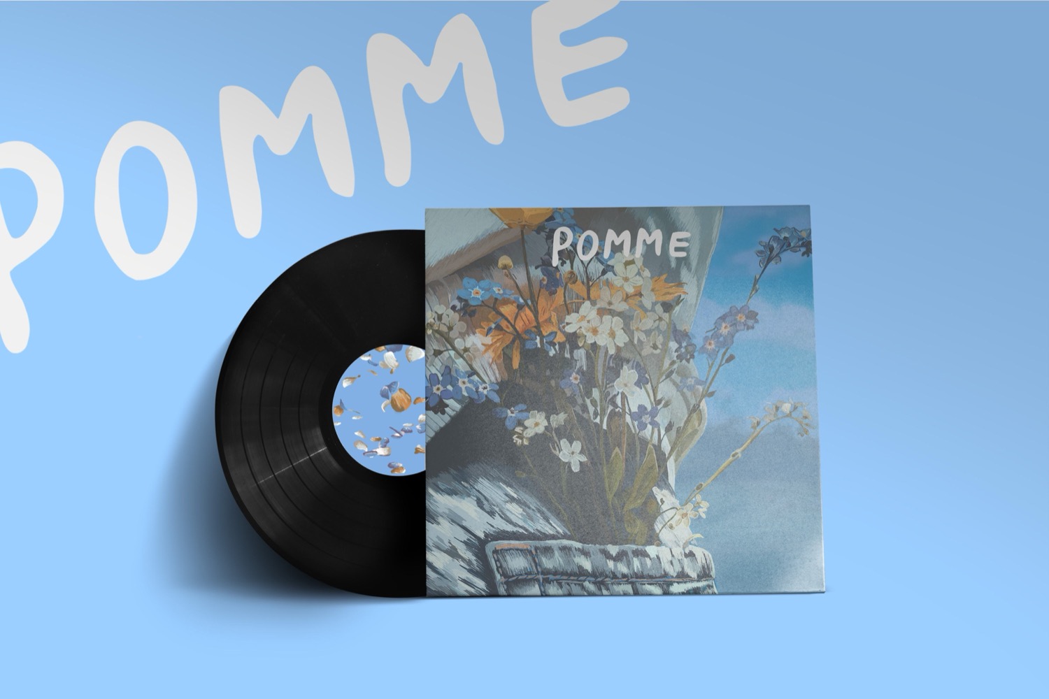 Le disque sorti de sa pochette sur fond bleu ciel, le nom Pomme peint à la main en arrière-plan.